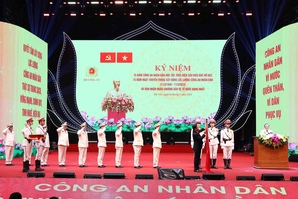 Chủ tịch nước Võ Văn Thưởng gắn Huân chương Bảo vệ Tổ quốc hạng Nhất lên lá cờ truyền thống Xây dựng lực lượng công an nhân dân. (Ảnh: Phạm Kiên/TTXVN)