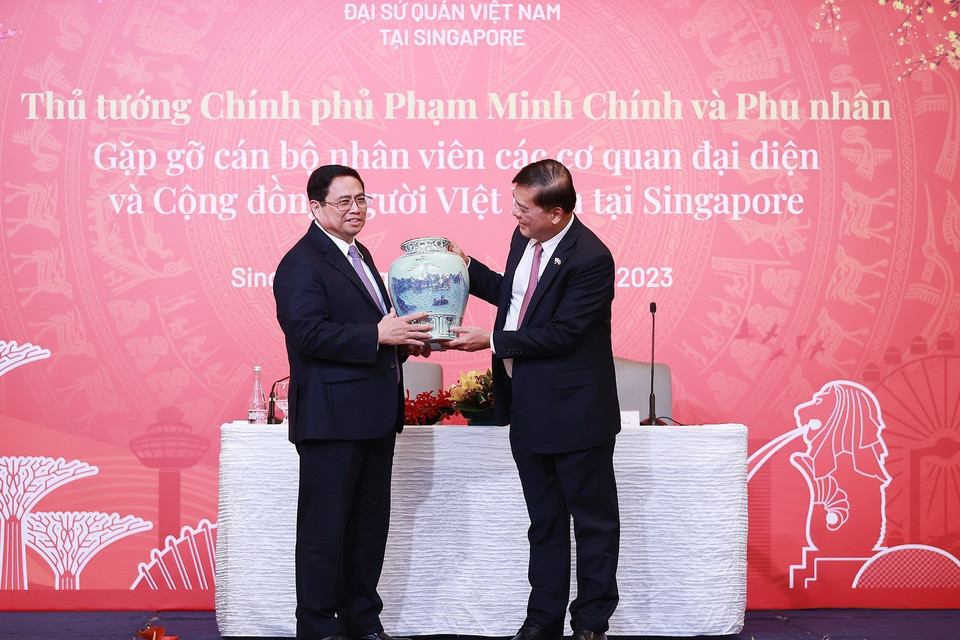 Thủ tướng Phạm Minh Chính tặng quà cho đại diện cán bộ, nhân viên các cơ quan đại diện Việt Nam tại Singapore. (Ảnh: Dương Giang/TTXVN)