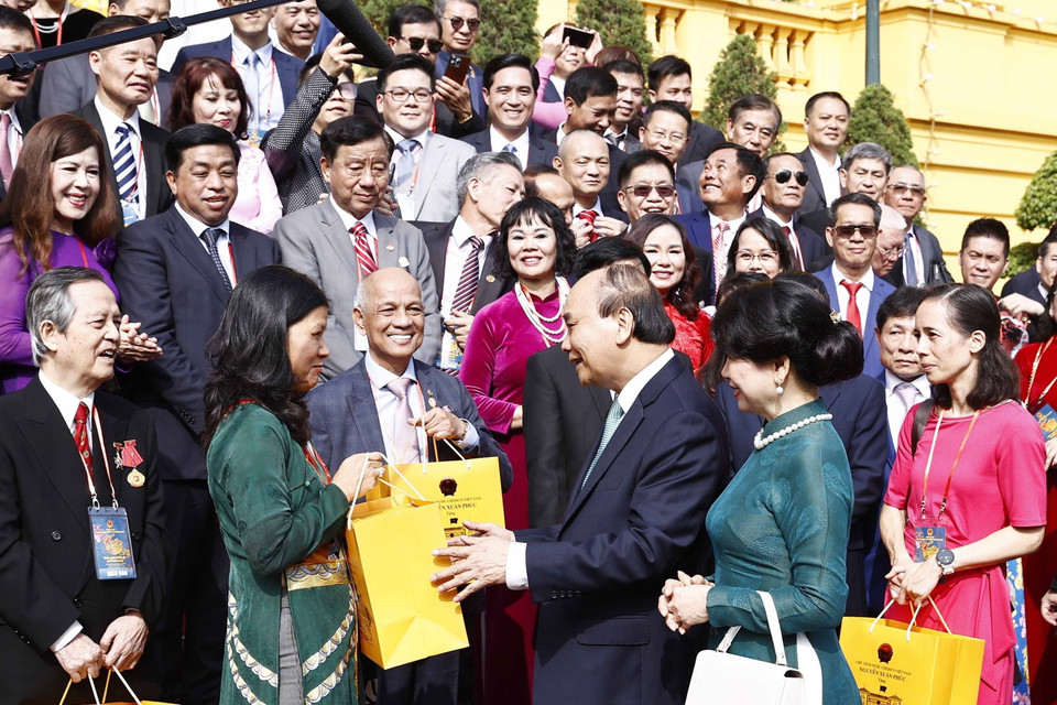 Chủ tịch nước Nguyễn Xuân Phúc tặng quà lưu niệm cho đại biểu kiều bào dự Chương trình Xuân Quê hương 2023, tại Phủ Chủ tịch. (Ảnh: Thống Nhất/TTXVN)