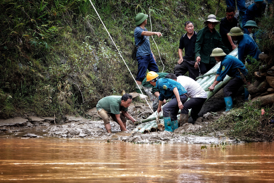 Nhờ có cáp treo mà lực lượng dân quân có thể vào giúp đỡ các hộ bị ảnh hưởng do mưa lũ. (Ảnh: Tuấn Anh/TTXVN)