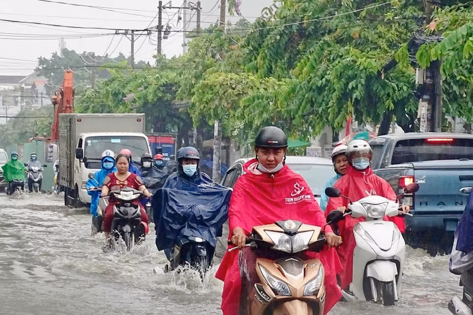 Người dân vượt dòng nước ngập trên đường Kha Vạn Cân, thành phố Thủ Đức. (Ảnh: Hồng Giang/TTXVN)