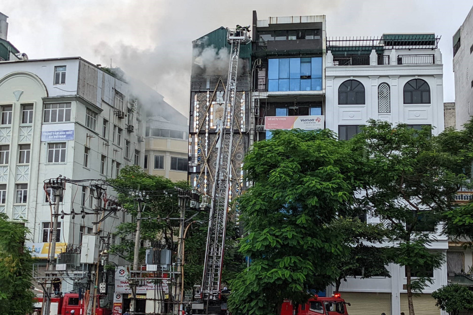 Lực lượng chức năng tìm cách tháo dỡ các bức tường ngăn để tiếp cận khu vực đám cháy ở bên trong, triển khai các biện pháp nghiệp vụ chữa cháy. (Ảnh: TTXVN phát)