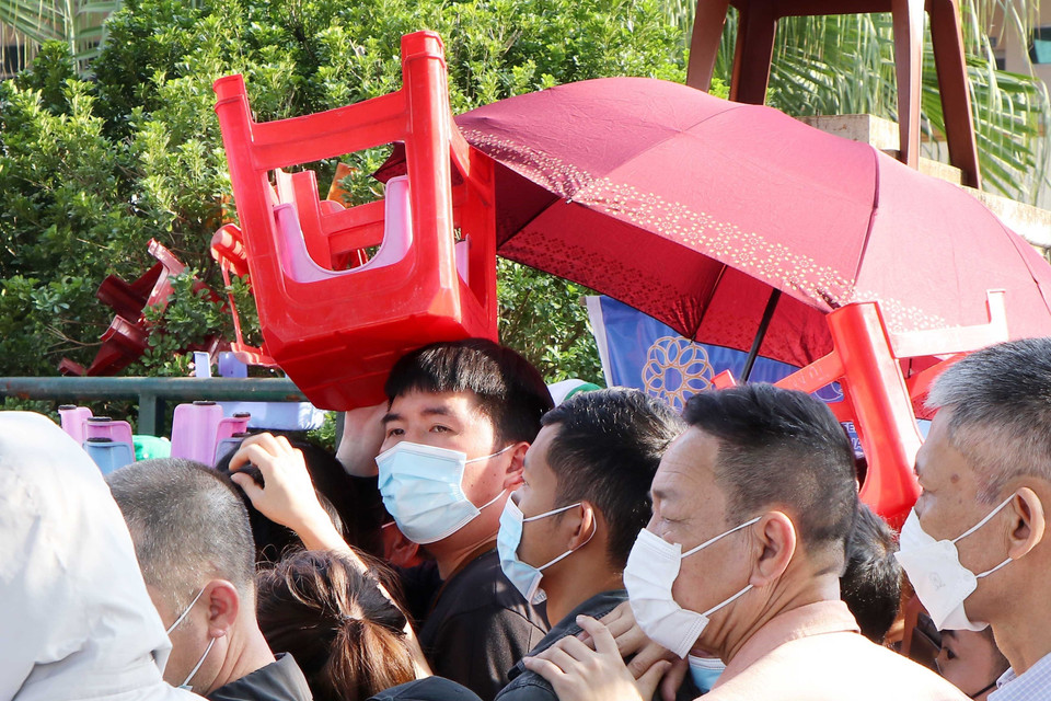 Một người xếp hàng mua vé dùng ghế để che nắng, chờ đến lượt được mua vé. (Ảnh: Trung Kiên/TTXVN)