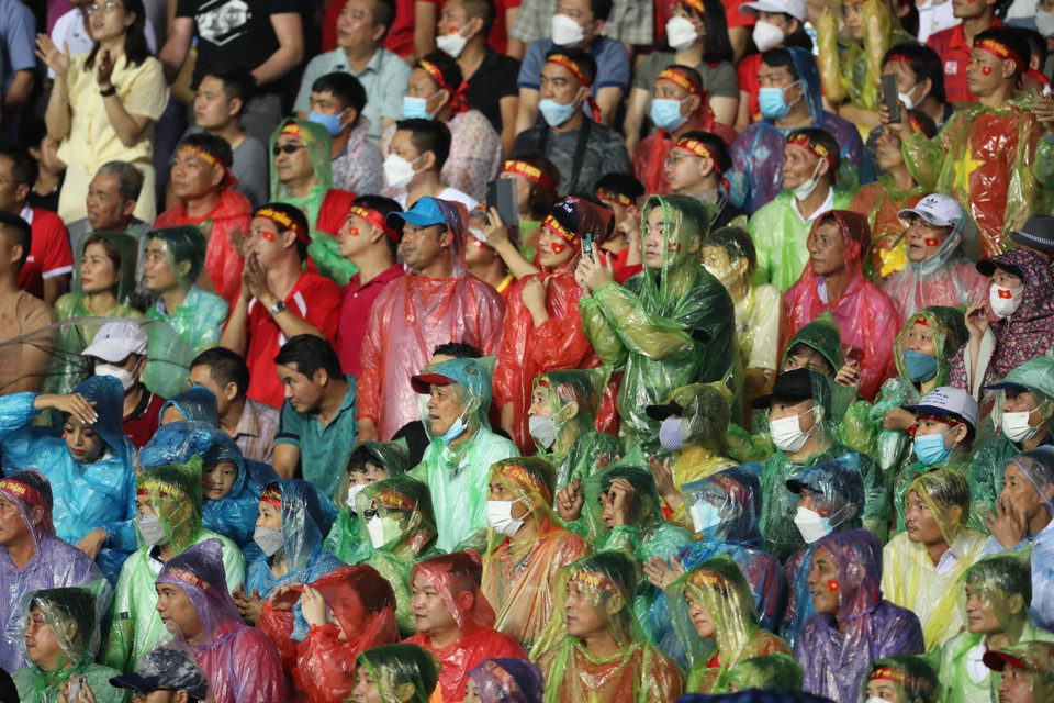 Khán giả đội mưa xem trận đấu. (Nguồn: TTXVN)