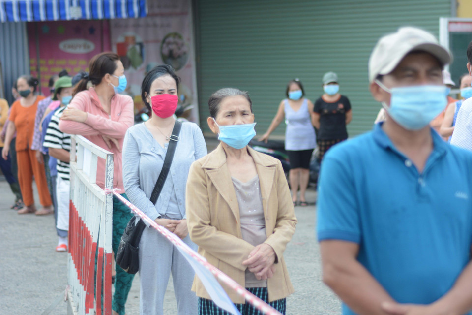 Tiểu thương xếp hàng, giữ khoảng cách khi lấy mẫu xét nghiệm. (Ảnh: Văn Dũng/TTXVN)