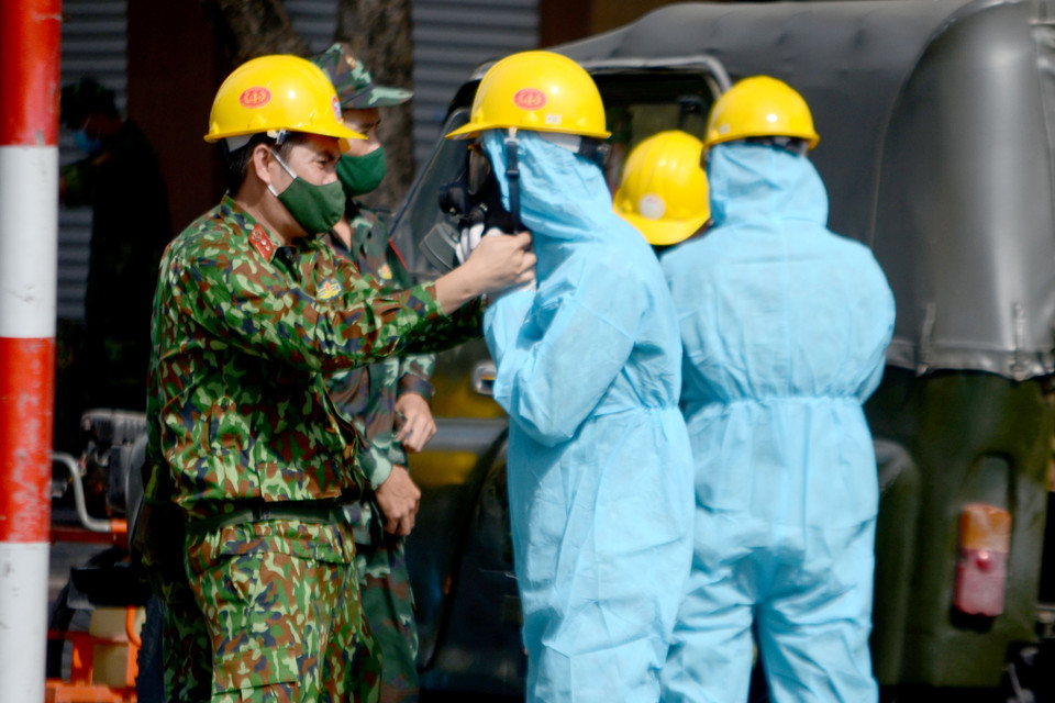 Sáng 6/5/2021, lực lượng Hóa học (Quân khu 5) tiến hành công tác tiêu độc, khử trùng, phòng ngừa COVID-19 tại khu vực xung quanh vũ trường New Phương Đông (đường Đống Đa, quận Hải Châu, thành phố Đà Nẵng). Hai xe phun xịt hóa chất chuyên dụng cùng hàng chục chiến sỹ đã phun xịt khử khuẩn khoảng 5.000m2 mặt đường, ngõ hẻm, các tòa nhà liền kề vũ trường. Trước đó, khu vực này đã bị phong tỏa sau khi quản lý ở vũ trường New Phương Đông là bà B.T.T (quê Đồng Nai) có kết quả xét nghiệm dương tính với virus SARS-CoV-2. Trước khi tiến hành phung xịt khử khuẩn, các chiến sỹ lực lượng Hóa Học (Quân khu 5) được mặc đồ bảo hộ đúng quy định. (Ảnh: Quốc Dũng/TTXVN)