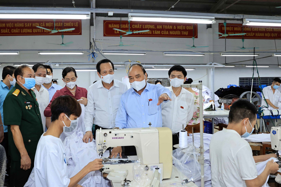 Chủ tịch nước Nguyễn Xuân Phúc đến thăm hỏi và tặng quà cho thương binh làm kinh tế giỏi Hoàng Văn Tuyên chủ doanh nghiệp may mặc Hoàng Tuyên. (Ảnh: Thống Nhất/TTXVN)