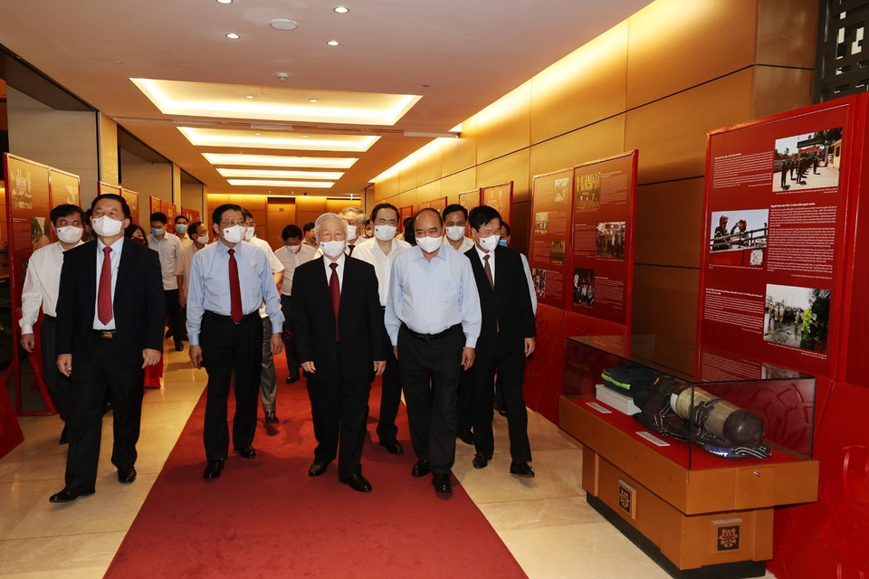 Sáng 12/6/2021, tại Hà Nội, Ban Bí thư Trung ương Đảng tổ chức Hội nghị sơ kết 5 năm thực hiện Chỉ thị số 05-CT/TW của Bộ Chính trị khóa XII, triển khai Kết luận số 01-KL/TW của Bộ Chính trị khóa XIII về tiếp tục thực hiện Chỉ thị số 05-CT/TW 'Về đẩy mạnh học tập và làm theo tư tưởng, đạo đức, phong cách Hồ Chí Minh' và Hội nghị nghiên cứu, học tập chuyên đề toàn khóa nhiệm kỳ Đại hội XIII của Đảng - chuyên đề năm 2021. Trong ảnh: Tổng Bí thư Nguyễn Phú Trọng, Chủ tịch nước Nguyễn Xuân Phúc, Thường trực Ban Bí thư Võ Văn Thưởng và các đại biểu thăm Triển lãm Những tấm gương bình dị mà cao quý trưng bày bên sảnh hội nghị. (Ảnh: Trí Dũng/TTXVN)