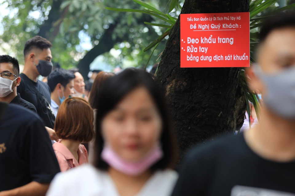 Mặc cho biển báo đeo khẩu trang tại Phủ Tây Hồ một số người vẫn không có ý thức bỏ khẩu trang nơi đông người. (Ảnh: Thành Đạt/TTXVN)