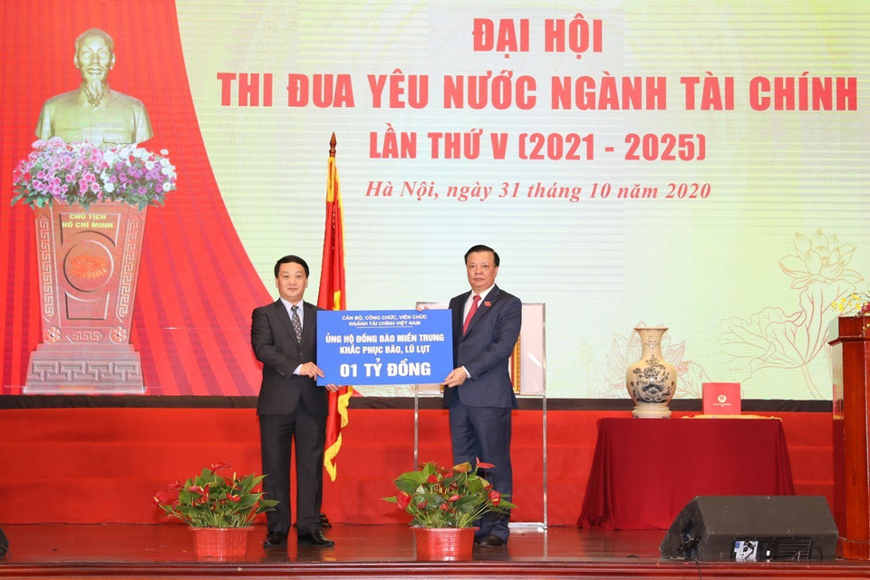 Bộ trưởng Bộ Tài chính Đinh Tiến Dũng trao tượng trưng cho ông Hầu A Lềnh, Phó Chủ tịch, Tổng Thư ký Ủy ban Trung ương Mặt trận Tổ quốc Việt Nam số tiền 1 tỷ đồng của cán bộ, công chức, viên chức ngành Tài chính ủng hộ đồng bào miền Trung khắc phục hậu quả bão, lũ lụt. (Ảnh: Phạm Hậu/TTXVN)