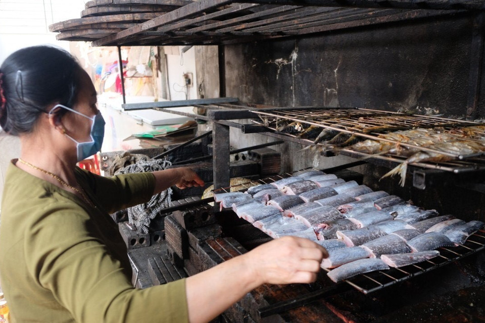 Đưa cá lên giàn nướng than. (Ảnh: TTXVN phát)