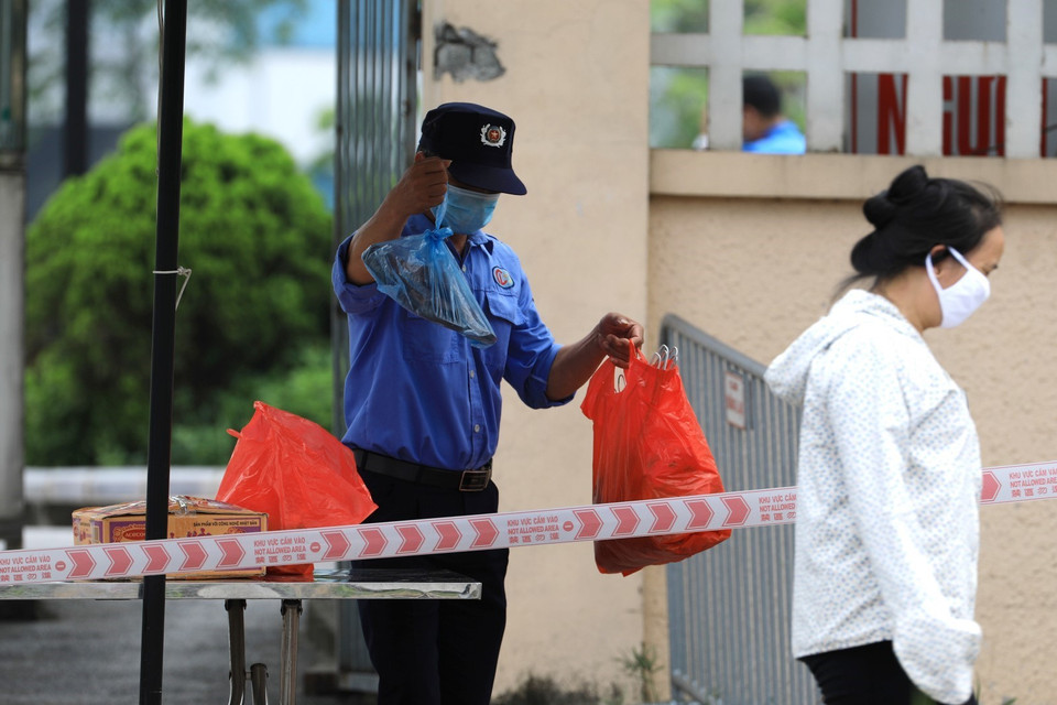 Người nhà tiếp tế nhu yếu phẩm cho bệnh nhân đều phải đặt tại chốt kiểm tra để nhân viên bệnh viện chuyển vào. (Ảnh: Thành Đạt/TTXVN)
