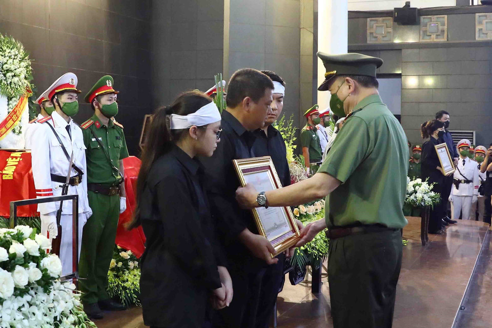 Đại tướng Tô Lâm, Ủy viên Bộ Chính trị, Bộ trưởng Bộ Công an trao Huân chương Chiến công hạng Nhất cho gia đình Thượng úy Đỗ Đức Việt (Cán bộ Đội Cảnh sát phòng cháy chữa cháy và cứu nạn cứu hộ, Công an quận Cầu Giấy). (Ảnh: Phạm Kiên/TTXVN)