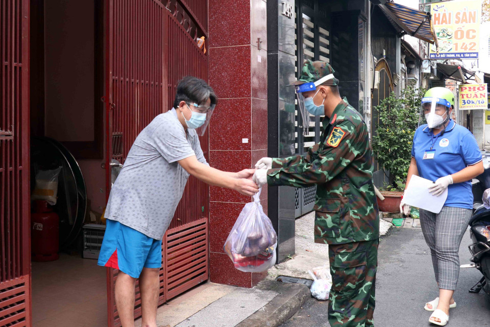 Cán bộ, chiến sỹ Sư đoàn 309 vận chuyển quà tặng nhu yếu phẩm sinh hoạt đến cho người dân tại phường 6, quận Tân Bình. (Ảnh: Xuân Khu-TTXVN)