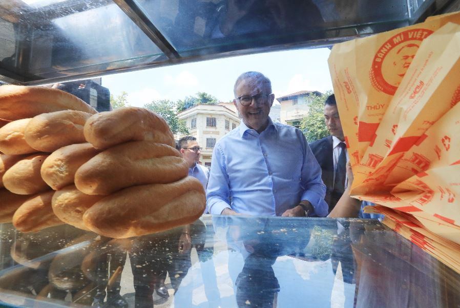 Thủ tướng Australia Anthony Albanese nghe giới thiệu về bánh mỳ patê truyền thống của Việt Nam. (Ảnh: Lâm Khánh/TTXVN)