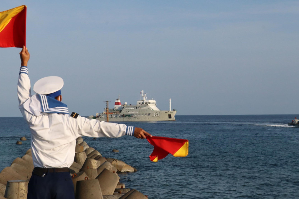 Chiến sỹ đảo Song Tử Tây phất cờ ra hiệu hướng dẫn xuồng máy chở cán bộ, chiến sỹ từ tàu Trường Sa 571 lên thăm đảo Song Tử Tây. (Ảnh: Sỹ Tuyên/TTXVN)