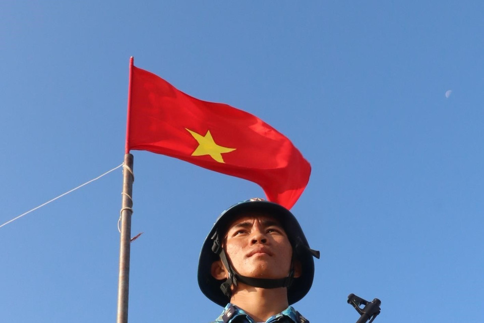 Chiến sỹ Nguyễn Xuân Quý - đảo Đá Tây A (quần đảo Trường Sa) nghiêm trang đứng gác dưới cờ Tổ quốc. (Ảnh: Sỹ Tuyên/TTXVN)