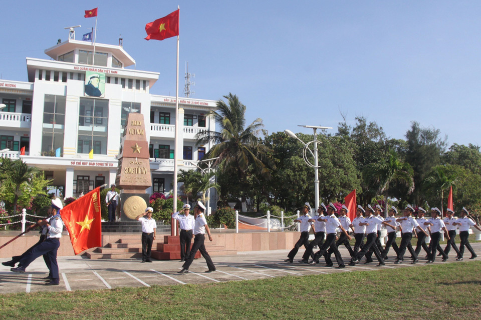 Đoàn duyệt đội ngũ mang lá 'Cờ Quyết thắng đảo Song Tử Tây' đi ngang qua cột mốc đảo Song Tử Tây trong lễ chào cờ trên đảo ngày 28/4/2021. (Ảnh: Sỹ Tuyên/TTXVN)