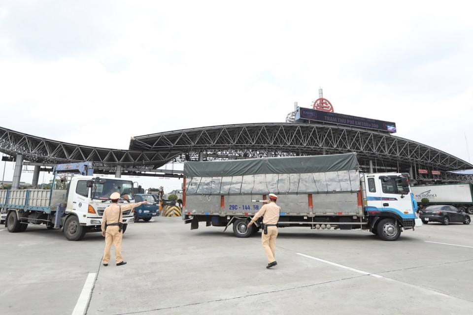 Lực lượng chức năng hướng dẫn các phương tiện quay đầu tại trạm thu phí Pháp Vân-Cầu Giẽ khi thực hiện Chỉ thị 17 của UBND thành phố. (Ảnh: Minh Quyết/TTXVN)
