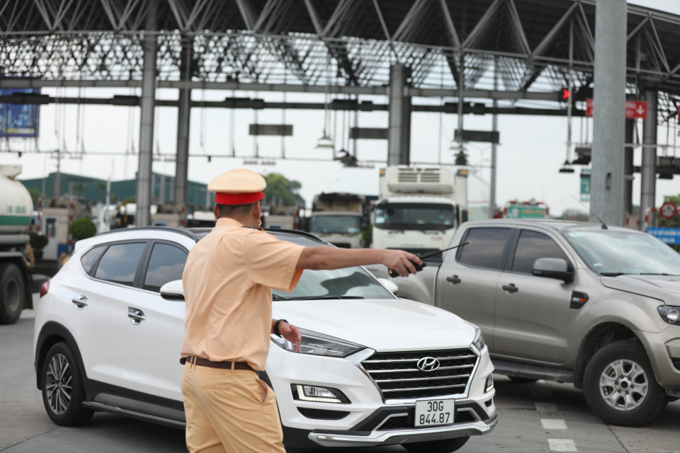Lực lượng chức năng hướng dẫn các phương tiện quay đầu tại trạm thu phí Pháp Vân-Cầu Giẽ khi thực hiện Chỉ thị 17 của UBND thành phố. (Ảnh: Minh Quyết/TTXVN)
