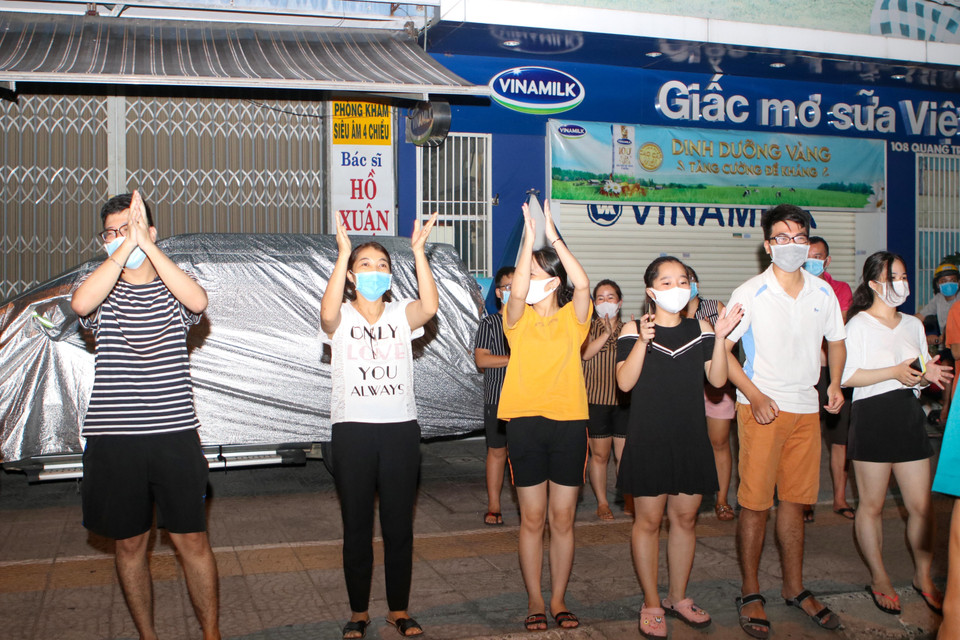 Người dân trên tuyến đường Quang Trung hào hứng chia sẻ niềm vui với các y bác sỹ Bệnh viện Chỉnh hình và Phục hồi chức năng Đà Nẵng sau khi lệnh phong tỏa được gỡ bỏ. (Ảnh: Trần Lê Lâm/TTXVN)