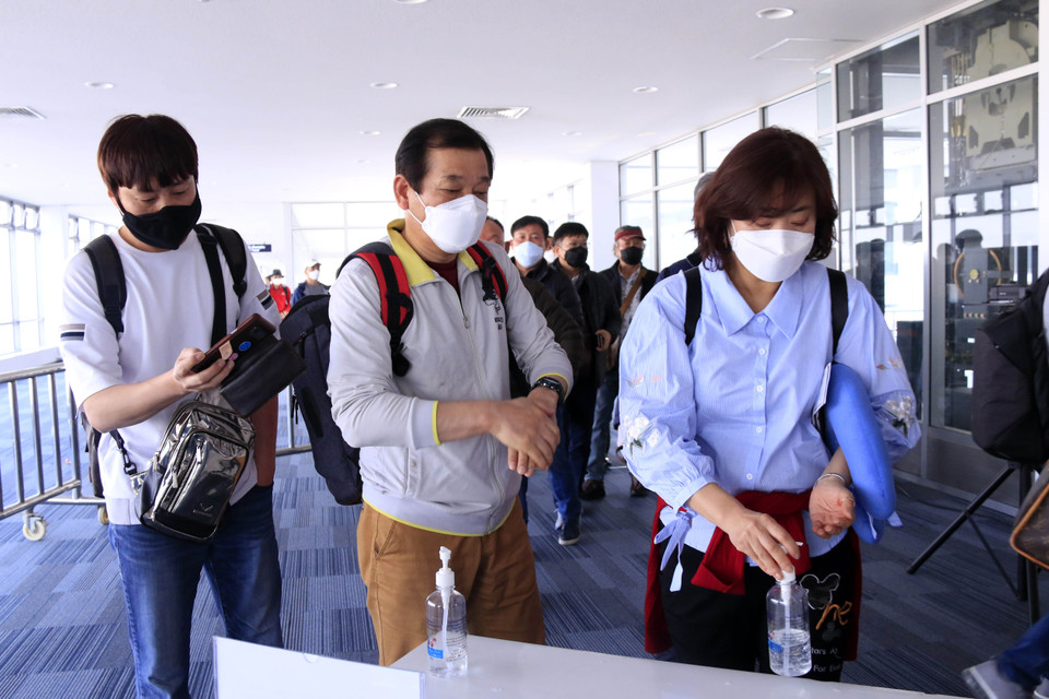 Hành khách đến Lào qua các cửa khẩu quốc tế sẽ được kiểm tra thân nhiệt, sau đó sẽ được yêu cầu sát khuẩn tay trước khi nhập cảnh Lào. (Ảnh: Phạm Kiên/Vietnam+)