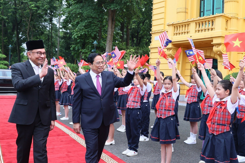 Thủ tướng Phạm Minh Chính và Thủ tướng Malaysia Anwar Ibrahim với thiếu nhi Thủ đô tại lễ đón. (Ảnh: Dương Giang/TTXVN)