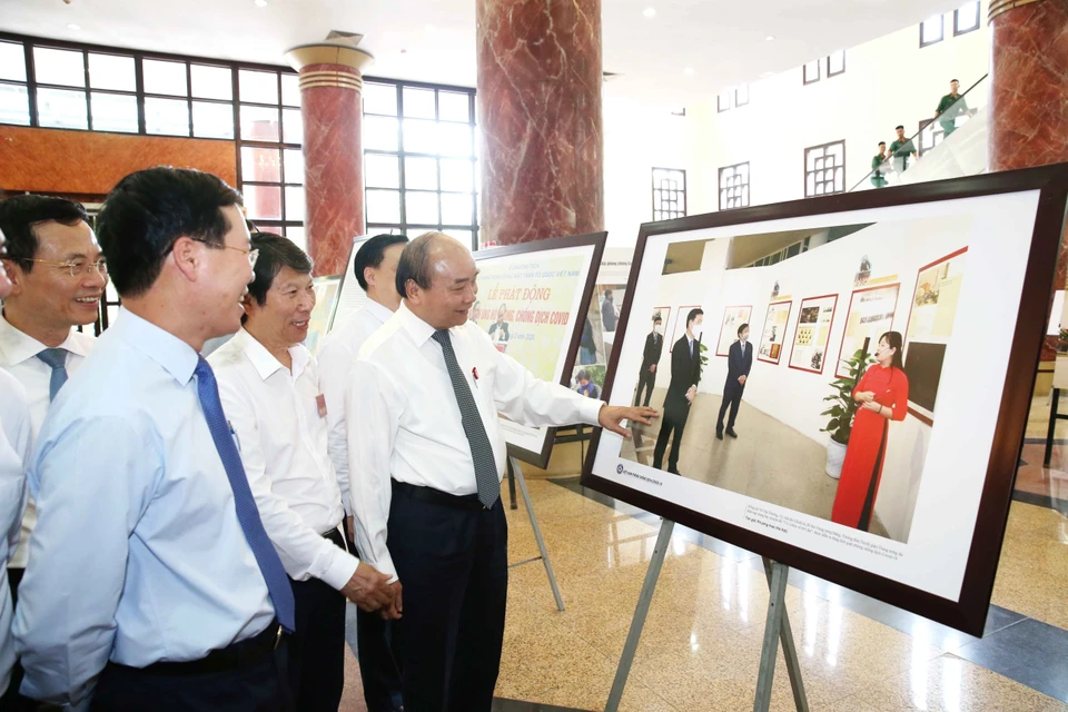 Thủ tướng Chính phủ Nguyễn Xuân Phúc và các đại biểu tham quan trưng bày ảnh 'Việt Nam phòng, chống dịch COVID-19.' (Ảnh: Phương Hoa/TTXVN) 