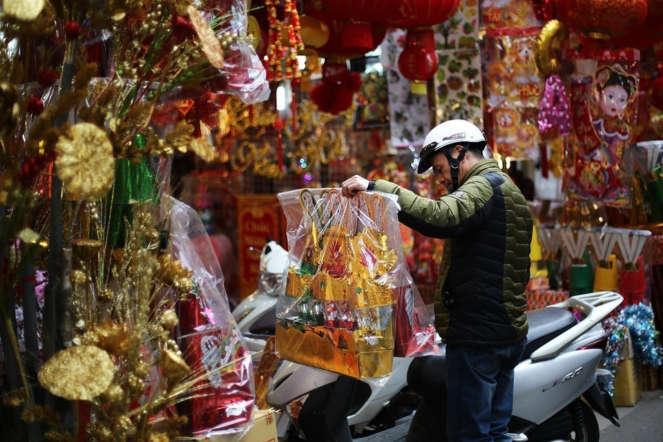 Người dân mua những vật phẩm truyền thống đồ cúng để cúng tiễn ông Công ông Táo về chầu trời. (Nguồn: TTXVN)