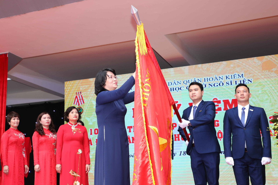 Phó Chủ tịch nước Đặng Thị Ngọc Thịnh gắn Huân chương Độc lập hạng Nhì lên lá cờ truyền thống của nhà trường. (Ảnh: Thanh Tùng/TTXVN)