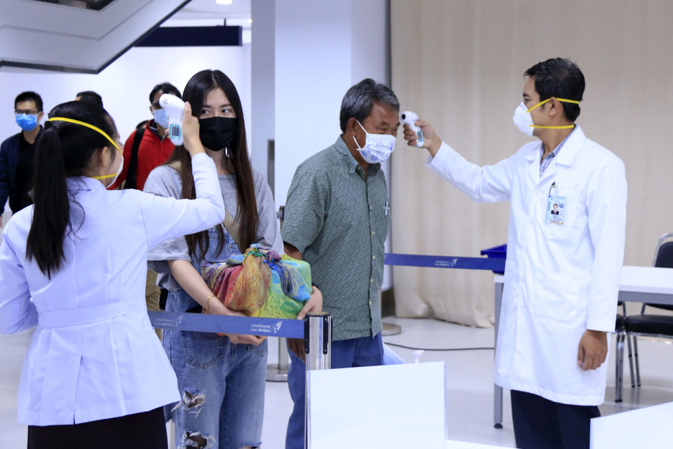 Hành khách đi trong nội địa cũng bị kiểm tra thân nhiệt chặt chẽ, sau đó sẽ được yêu cầu sát khuẩn tay trước khi vào khu an ninh. (Ảnh: Phạm Kiên/Vietnam+)