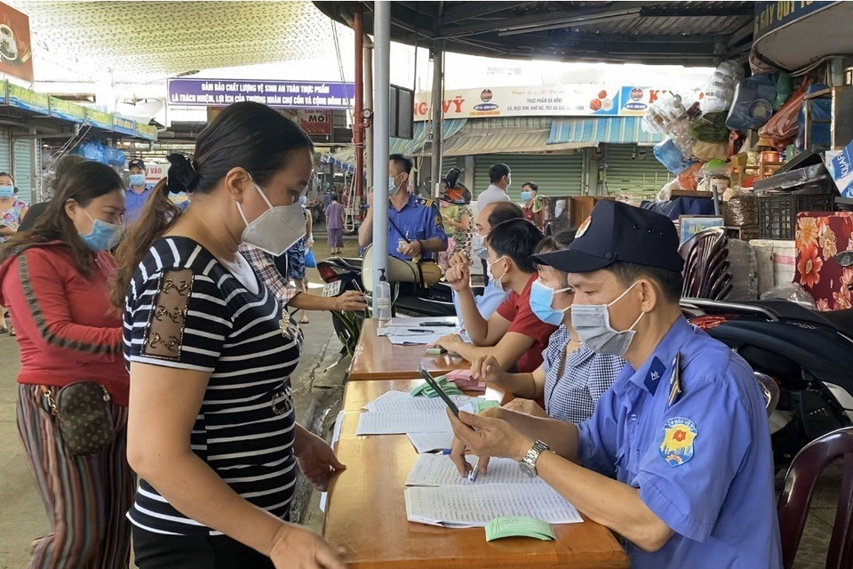 Tại chợ Cồn nhiều tiểu thương xếp hàng lấy thẻ buôn bán luân phiên tại chợ. (Ảnh: Văn Dũng/TTXVN)