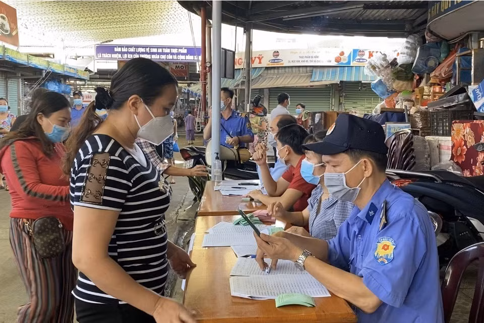 Tại chợ Cồn nhiều tiểu thương xếp hàng lấy thẻ buôn bán luân phiên tại chợ. (Ảnh: Văn Dũng/TTXVN)