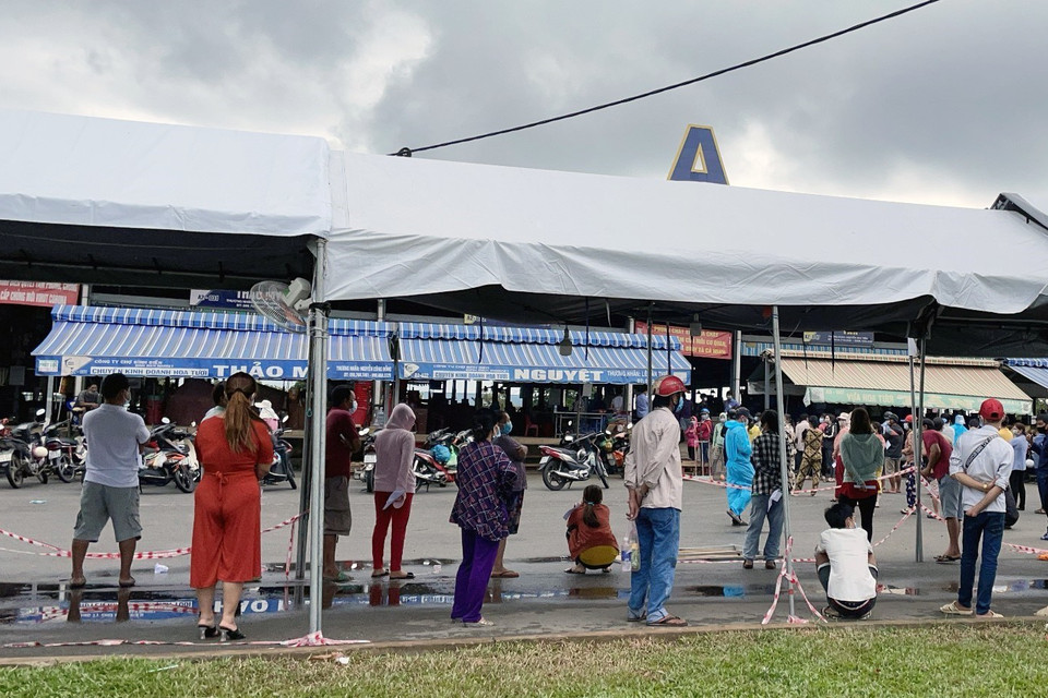 Thương nhân, tiểu thương chợ Bình Điền xếp hàng chờ lấy mẫu tầm soát COVID-19. (Ảnh: TTXVN phát)