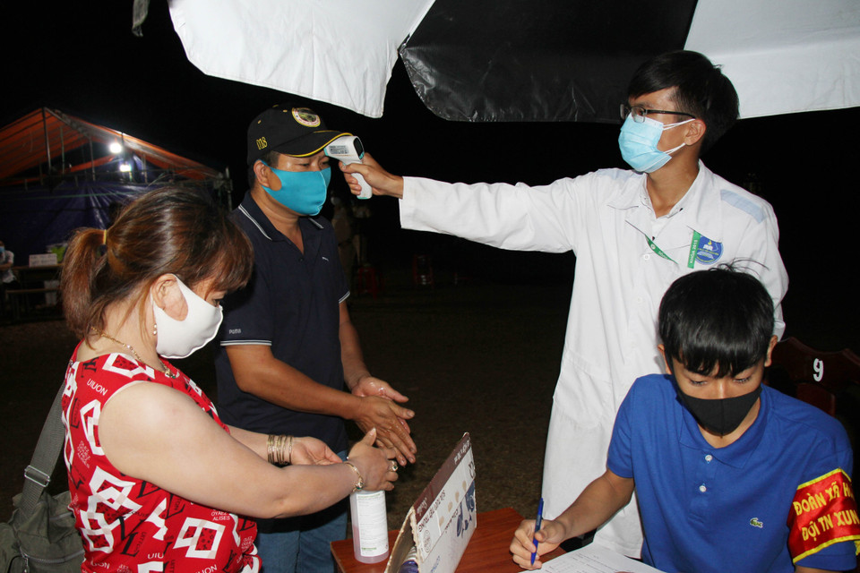 Người dân được sát khuẩn tay và kiểm tra thân nhiệt tại chốt kiểm dịch trên đường Hồ Chí Minh, xã Hòa Phú, thành phố Buôn Ma Thuột, tỉnh Đắk Lắk. (Ảnh: Tuấn Anh/TTXVN)