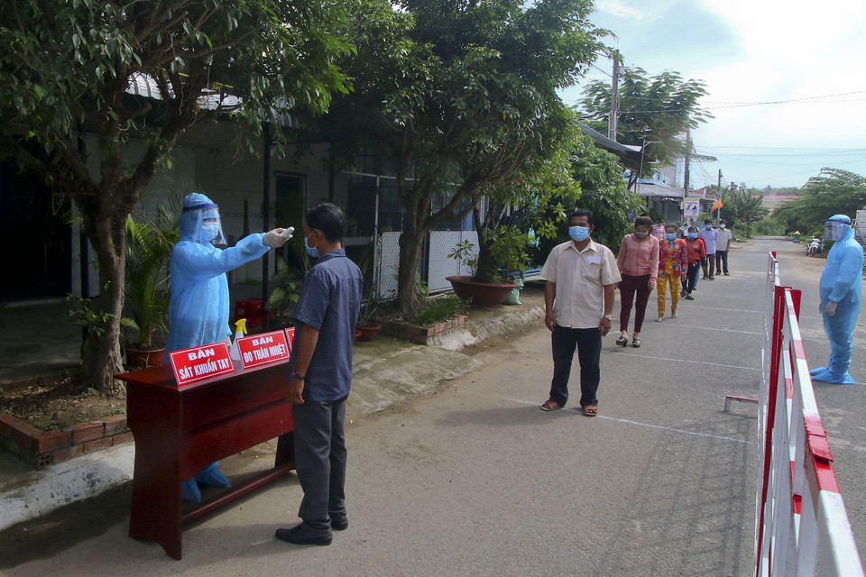 Đo thân nhiệt cho cử tri vùng cách ly y tế trong khu dân cư (khu vực phong tỏa) trước khi tiến hành bỏ phiếu bầu cử. (Ảnh: Duy Khương/TTXVN)