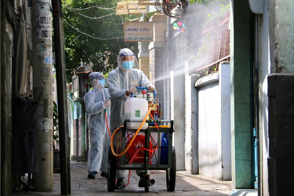 Lực lượng chức năng phường 11, quận 3 tăng cường phụn xịt khử khuẩn khu vực vùng vàng để chuyển hóa thành vùng xanh. (Ảnh: Thanh Vũ/TTXVN)