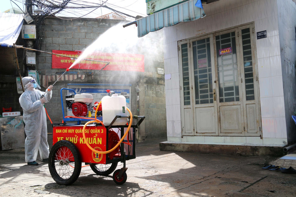 Lực lượng chức năng phường 11, quận 3 tăng cường phun xịt khử khuẩn khu vực vùng vàng để chuyển hóa thành vùng xanh. (Ảnh: Thanh Vũ/TTXVN)