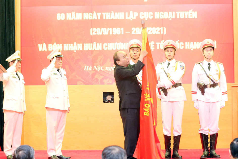 Chủ tịch nước Nguyễn Xuân Phúc gắn Huân chương Bảo vệ Tổ quốc hạng Nhì lên cờ truyền thống của Cục Ngoại tuyến. (Ảnh: Phạm Kiên/TTXVN)