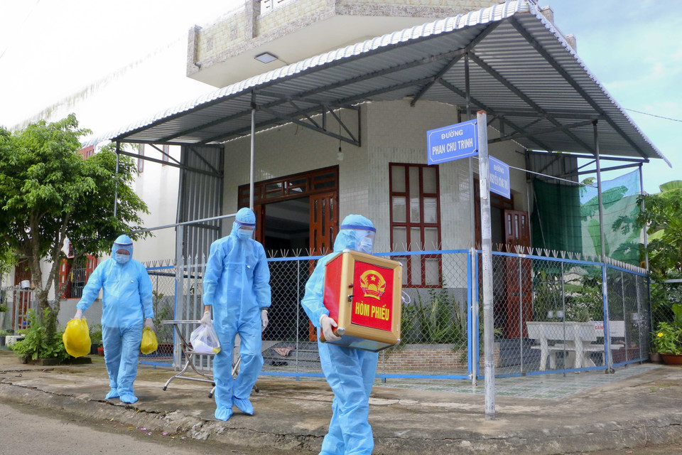 Tổ bầu cử lưu động di chuyển hòm phiếu phụ có khử khuẩn bằng tia cực tím đến cử tri đang thực hiện cách ly tại nhà. (Ảnh: Duy Khương/TTXVN)