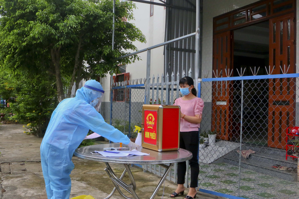 Cử tri đang thực hiện cách ly tại nhà tham gia bầu cử với thùng phiếu phụ được đưa tới tận nhà. (Ảnh: Duy Khương/TTXVN)