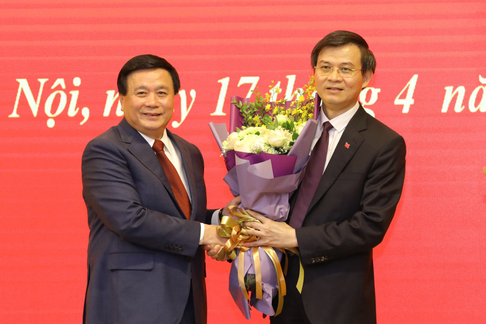 Ủy viên Bộ Chính, Chủ tịch Hội đồng Lý luận Trung ương Nguyễn Xuân Thắng tặng hoa Ủy viên Trung ương Đảng, Tổng biên tập Tạp chí Cộng sản Đoàn Minh Huấn. (Ảnh: Văn Điệp/TTXVN)