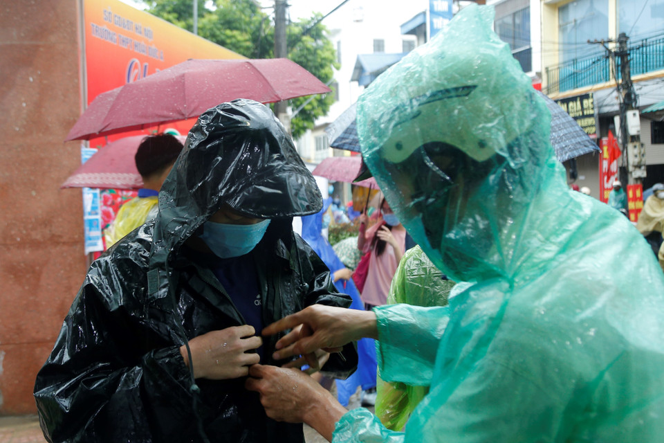 Nhiều em học sinh đến từ sớm nhờ phụ huynh đưa đi, song vẫn không thể tránh được con mưa nặng hạt. (Ảnh: HIển Nguyễn/Vietnam+)