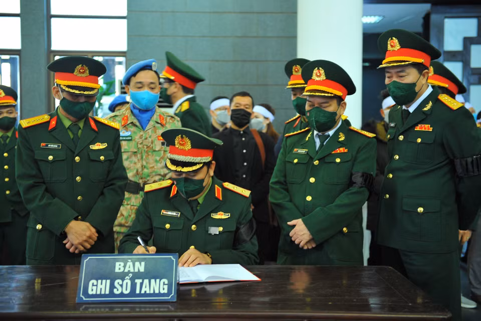 Lãnh đạo Bộ Quốc phòng viết cảm tưởng vào sổ tang tại Lễ viếng liệt sỹ, Trung tá Đỗ Anh. (Ảnh: Minh Đức/TTXVN)