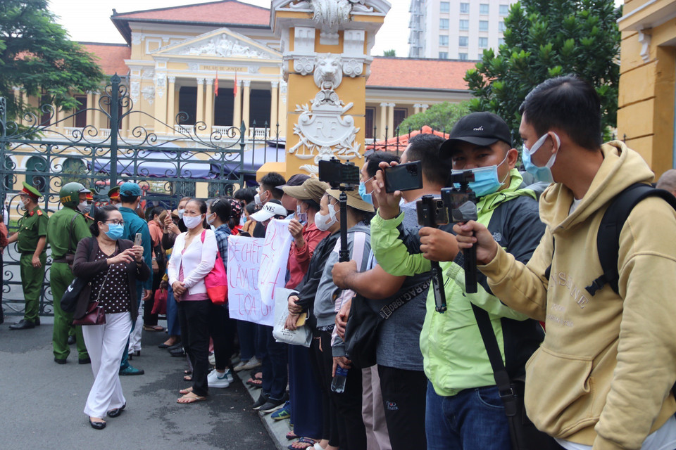 Người dân và phóng viên theo dõi phiên tòa từ bên ngoài khuôn viên Tòa án. (Ảnh: Thanh Vũ/TTXVN)