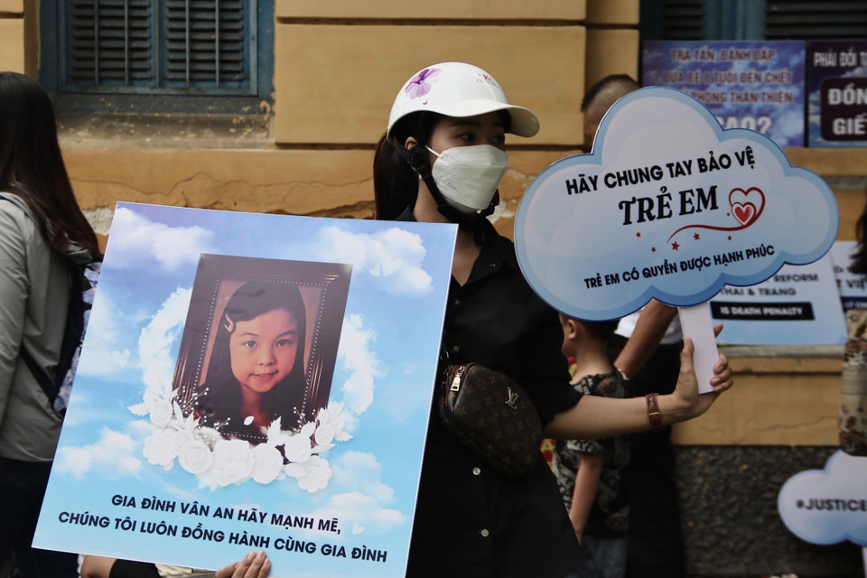 Người dân cầm biểu ngữ ủng hộ người bị hại. (Ảnh: Thanh Vũ/TTXVN)