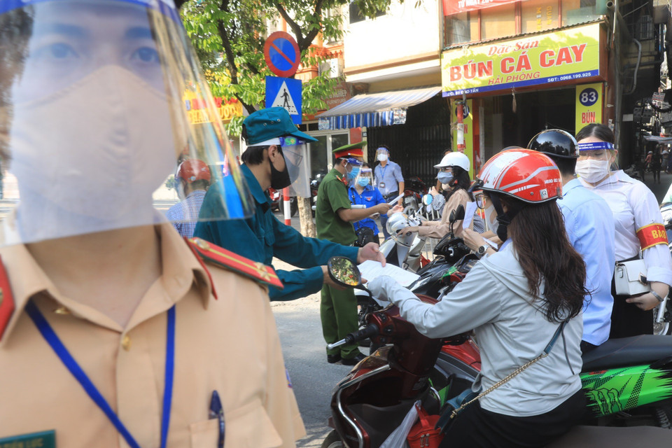 Lực lượng chức năng kiểm tra giấy tờ tùy thân và xác nhận đi làm, ra ngoài của cơ quan với người dân lưu thông trên đường Đào Tấn, Hà Nội, sáng 28/7. (Ảnh: Lâm Khánh/TTXVN)