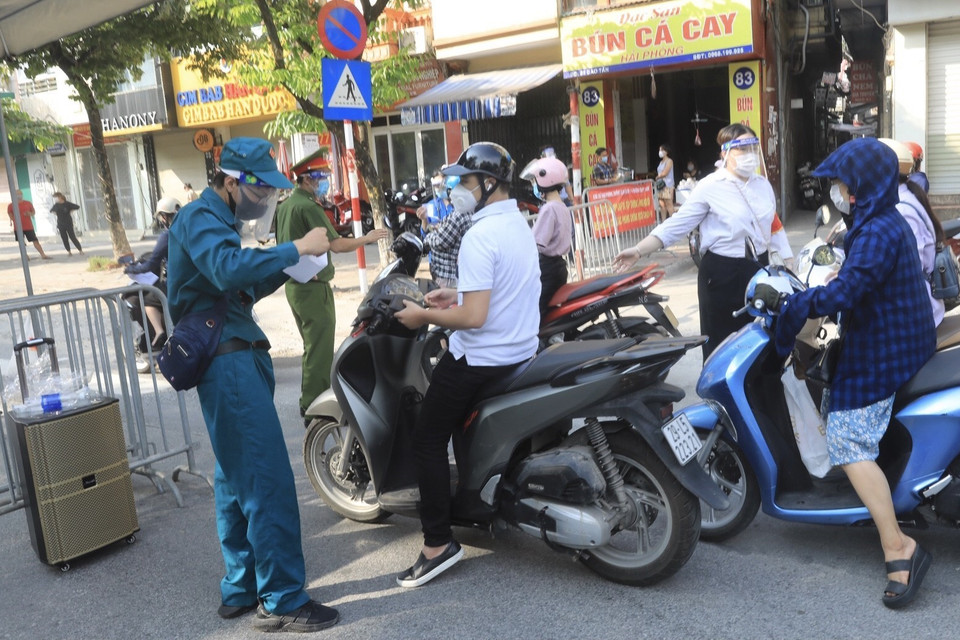 Người dân xuất trình giấy tờ cần thiết khi qua chốt kiểm tra. (Ảnh: Lâm Khánh/TTXVN)