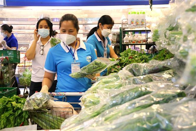 Chủ tịch Hội Liên hiệp phụ nữ Quận 3 Đoàn Thị Cẩm Tú giúp dân đi chợ mua thực phẩm trong những ngày thực hiện giãn cách xã hội. (Ảnh: Thanh Vũ/TTXVN)