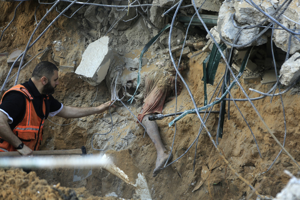 Nhân viên y tế Palestine tiếp cận một thi thể bị chôn vùi trong đống đổ nát của một ngôi nhà bị sập của gia đình al-Tanani ở Beit Lahia, phía bắc Dải Gaza. (Ảnh: AFP)